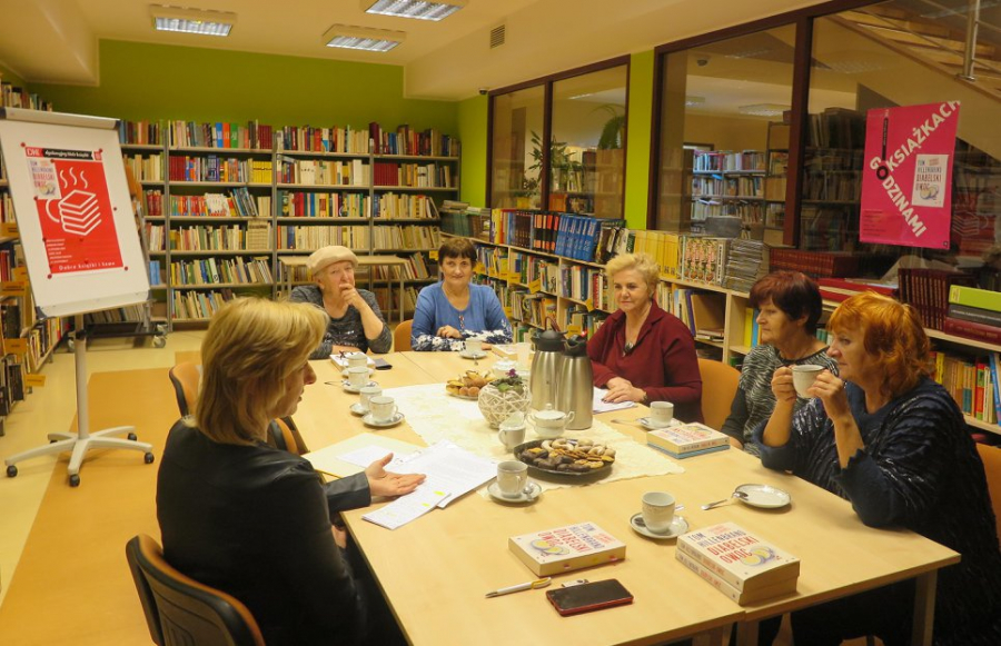 Kilka kobiet rozmawiający przy stole na temat książki w przytulnej atmosferze Biblioteki