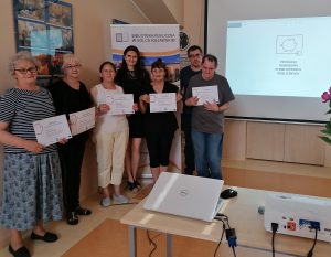 Na zdjęciu widzimy 7 osób ustawionych koło siebie. W dłoniach trzymają certyfikaty ukończenia kursu edukacji finansowej.